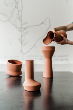 female hands pouring water from brown ceramics