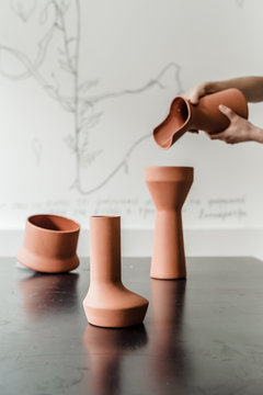 Hands holding brown ceramic jar pouring water in handmade crockery