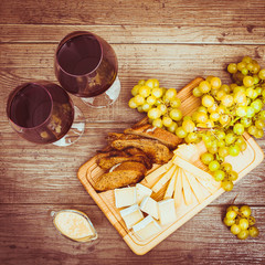 Cheese, toasted brown bread, two glasses of red wine. Top view. Sepia toned. Horizontal.