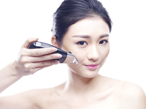 young asian woman using a face spa device