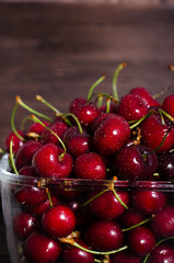 Fresh cherry fruits in a glass on a wooden table. Free space for your text.