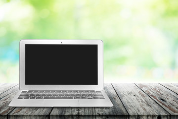 laptop with blank screen on wooden table outdoors and garden blu