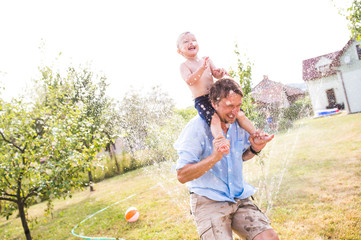 Little boy with his father at the sprinkler, summer