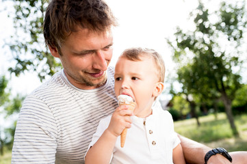 Father and son eating ice cream, sunny summer garden