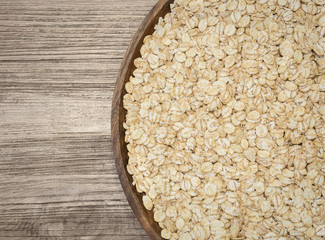 Barley flakes in wooden tray on wooden background