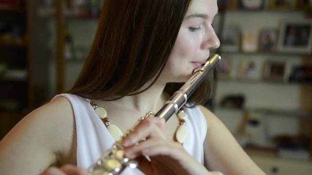 Young girl playing the flute in the living room