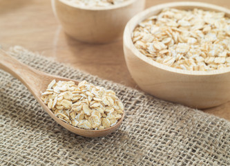 Wheat flakes in wooden spoon on wooden background - Raw food ingredients