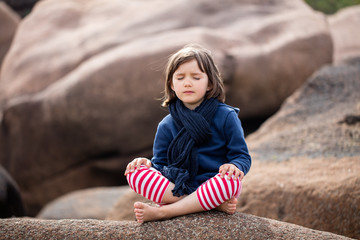meditating child with eyes closed sitting, relaxing for yoga exercise