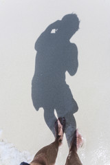 man is throwing shadow to the fine sand of the beach