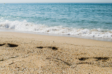 Footsteps on the sand beach, sea on background, seashore