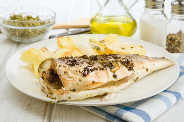baked sea bass with potatoes in tray