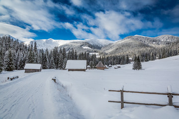 Wooden cottages in the valley Chocholowska at sunrise in winter, Tatra Mountains, Poland