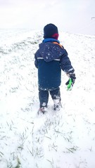 Fototapeta na wymiar Kind spaziert in winterlicher Kleidung durch Schnee