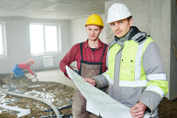 foreman builder and construction worker with blueprint in indoor apartment
