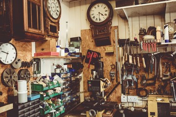 Horologists workshop with clock repairing tools, equipment and clocks on the wall