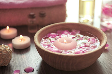 Obraz na płótnie Canvas Petals in bowl with candles on wooden background