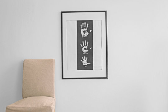 Family hand prints in frame hanging on wall in room
