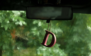 Air freshener hanging in the car on green natural background