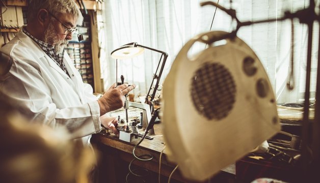 Side view of horologist working in workshop