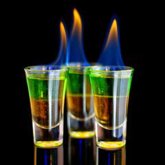 Burning Green cocktail in shot glass on black background