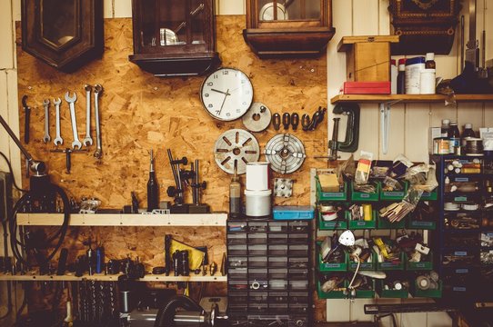 Horologists workshop with clock repairing tools, equipment and clocks on the wall