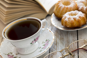 Coffee with cupcakes and book on the wooden table