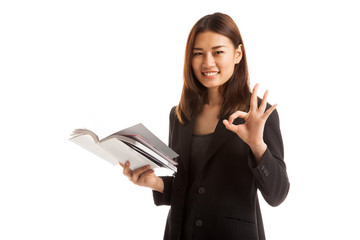 Young Asian business woman show OK with a book.