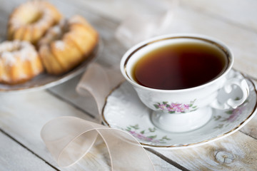 Coffee with cupcakes and pink ribbon on the wooden table 