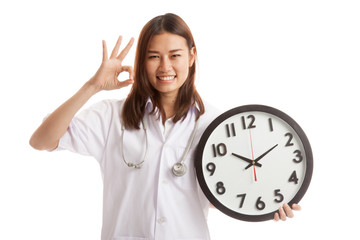 Young Asian female doctor show OK with a clock.