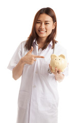 Young Asian female doctor point to a pig bank coin.