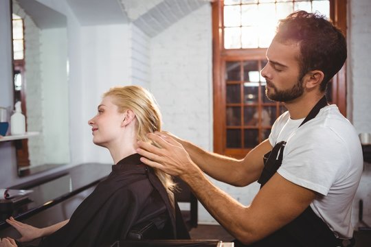 Handsome hair stylist styling woman hair