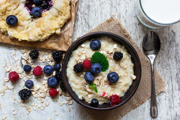 Obraz na płótnie Canvas healthy breakfast with bowl of oatmeal, homemade blueberry cake and milk