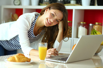Obraz na płótnie Canvas Young woman sitting near desk in the kitchen