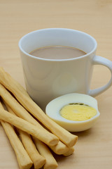 Cup of coffee and grissini, boiled egg sliced in halves
