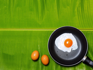 Fried Egg in the pan on banana leaf.