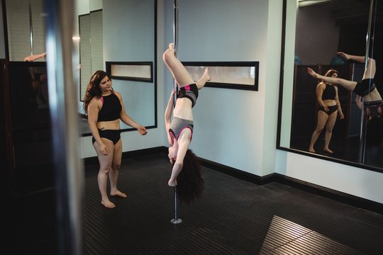 Instructor assisting pole dancer with a correct pose