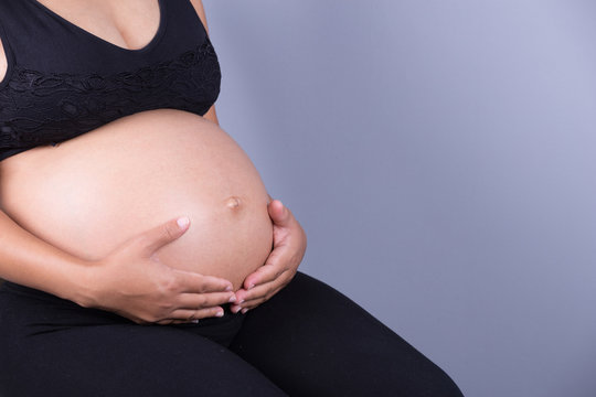 Close-up of pregnant woman belly with her hand