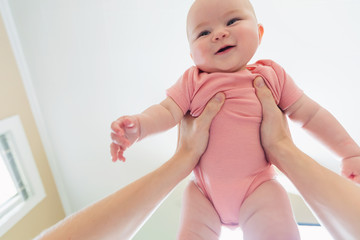 Happy infant baby girl being held up in the air