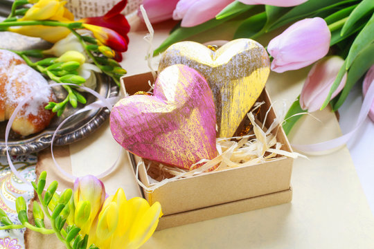 Easter decorations: hearts in paper box, spring flowers around.
