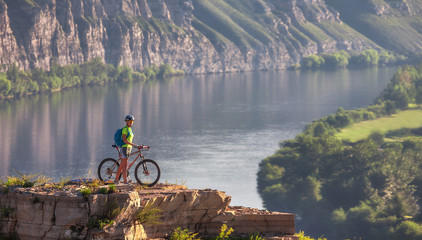 Young woman standing in mountain with bicycle above river