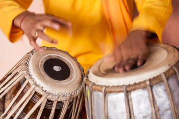A young boy playing on traditional Indian tabla drums. 
