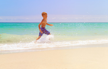 little boy running splashing water on beach