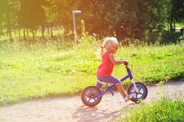 cute little girl riding runbike in summer