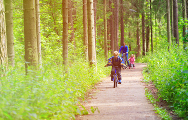 Obraz premium family sport - father and kids riding bikes in summer forest