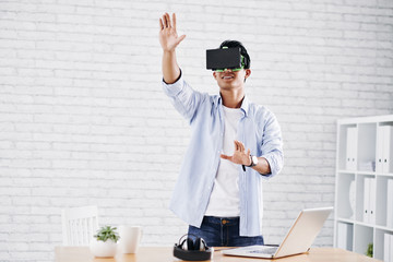 Asian man in virtual reality glasses working in office