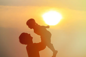 Father and little daughter silhouettes play at sunset