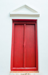 red window on white wall with gable in temple