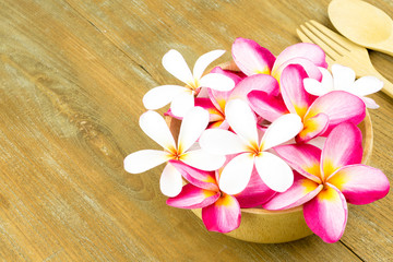 Topview Plumeria in wooden bowl spoon and frok on wooden backgro