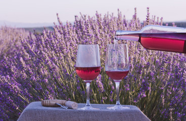 Rose wine poured into glasses in lavender field