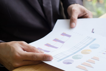 Image of document with charts on hand.